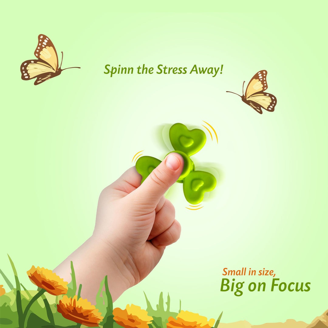 A hand spins a small green shamrock-shaped stress ball with heart-shaped cutouts, set against a light green background with decorative butterflies, flowers, and text reading 'Spinn the Stress Away!' and 'Small in size, Big on Focus.'.